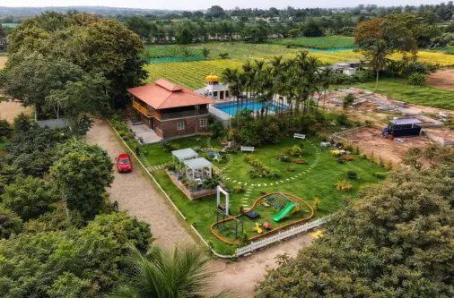 Aerial view of managed farmland project near Bangalore showing farmhouse, greenery, and plantation layout